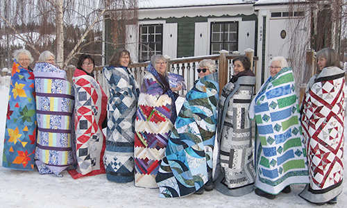 Bear's Paw Quilt staffers  wrapped in their quilts